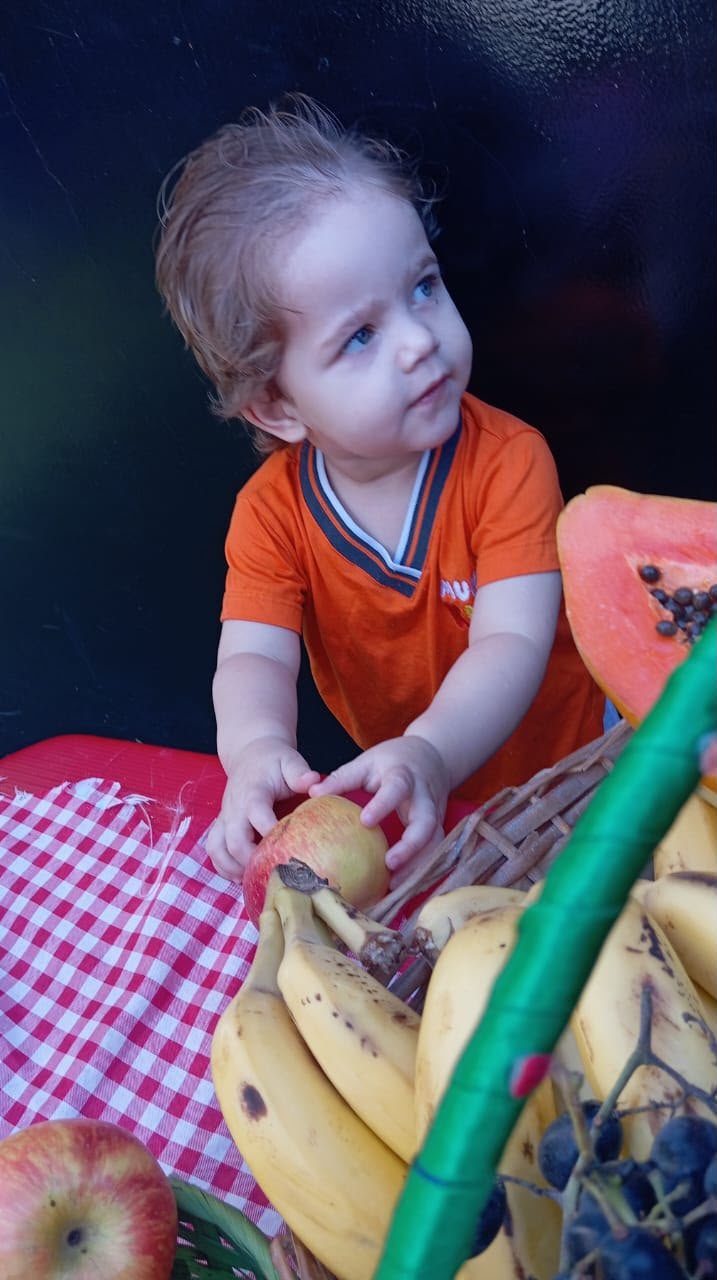 Criança explorando frutas em atividade de horta e alimentação
